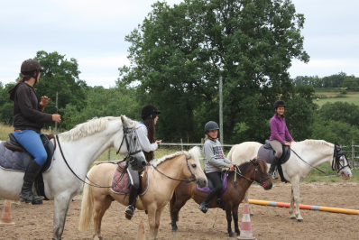 Quatre adolescentes à cheval et à poney dans une carrière